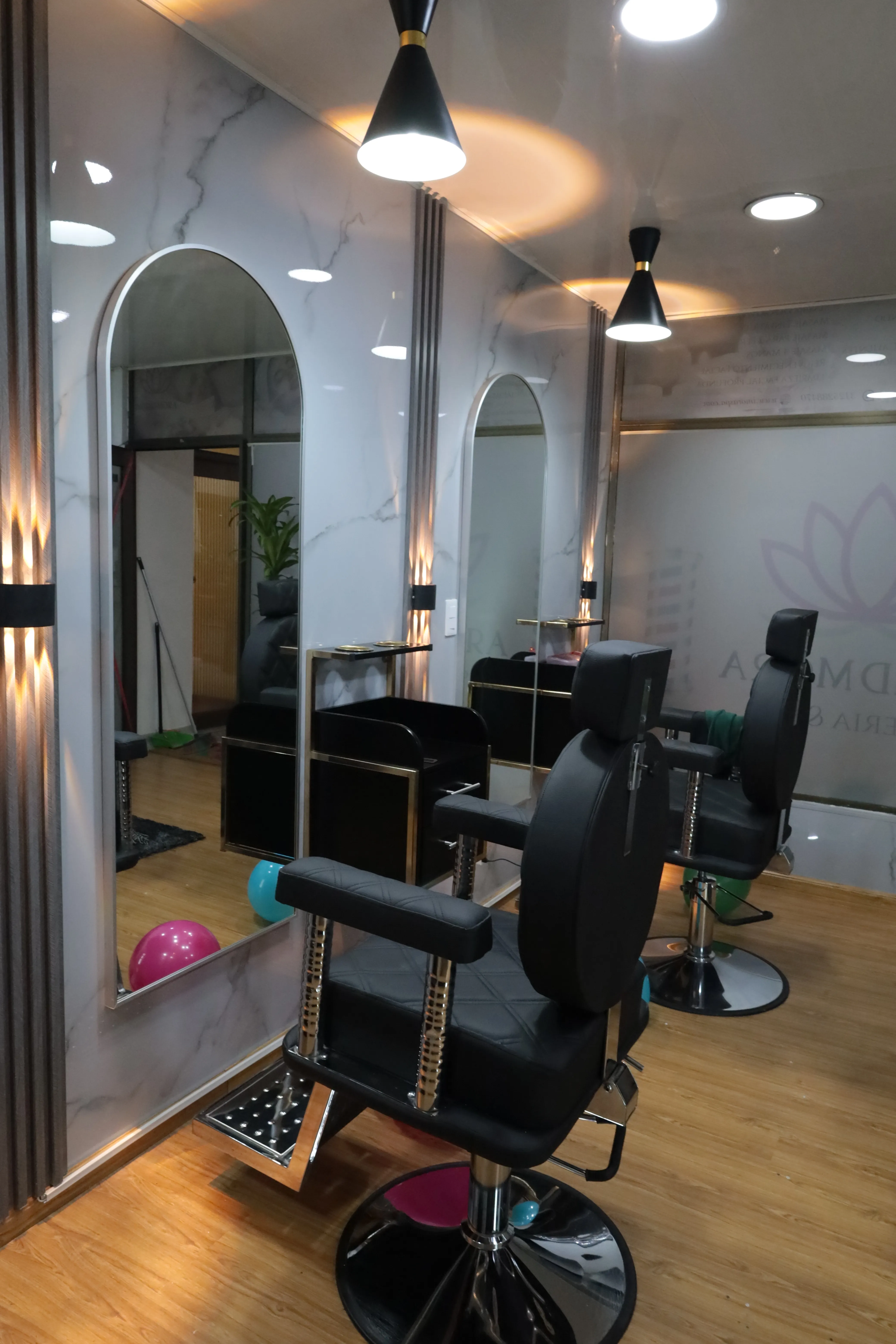 Sillones de barbería y espejos con arco en el salón de Imora